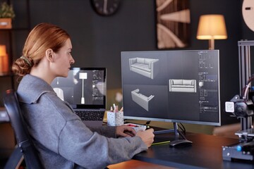 Fototapete - Woman sitting at desk, focusing on 3D modeling software displayed on her computer screen. Office environment includes various technological gadgets and modern decor elements