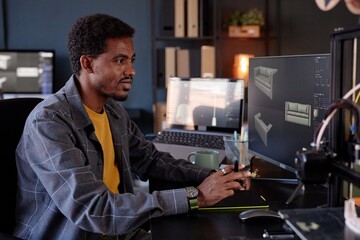 Leinwandbilder - Man working at desk using computer to design 3D models of furniture Lighting from screens and multiple monitors enhancing workspace ambiance