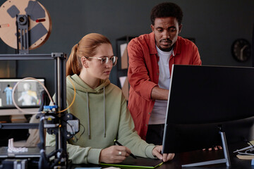 Leinwandbilder - Two colleagues collaborating on project in modern workspace, involving 3D printing and computer workstation, engaging in discussion, sharing ideas, and using technology