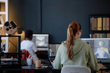 Leinwandbilder - Individuals engaged in coding and designing 3D models in modern office environment with various gadgets and tools. Shelves filled with files and folders in background