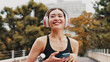 © peopleimages.com - Thinking, woman and headphones with phone in city, listening to music and fitness podcast. Female athlete, mobile and streaming radio with exercise routine, training website and break on Japan bridge
