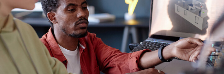 Leinwandbilder - Portrait of an African American man working with a colleague on an architectural design displayed on a computer screen, during a project discussion in the office