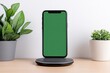 © Thanyarat - A high-resolution shot of a modern smartphone on a wireless charging pad in a minimalist workspace