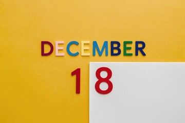 Poster - December 18th displayed with colorful letters on a yellow background