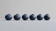 © Darunee - A group of fresh blueberries arranged in a straight line on a plain white background