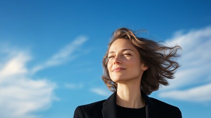 Wall Mural - sunny day with a woman enjoying the breeze and looking upwards against a bright blue sky