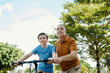 © DragonImages - Grandfather teaching his son to ride a bike during their leisure time outdoors