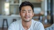 © Z A C - A young Asian man with dark hair and a white shirt sits in a blurred cozy living room setting.
