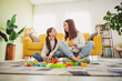 © deagreez - Young mother and daughter enjoying a playful time with blocks on a relaxing spring day in their cozy living room.
