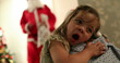 © Marco - Tired little girl yawning looking at santa claus at home hugging mom feeling shy