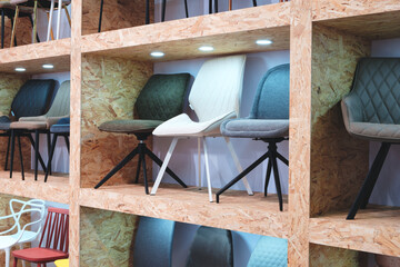 Poster - A row of wooden shelves with a variety of chairs on them. The chairs are of different colors and styles