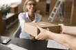 © fizkes - Hands of customer receiving parcel in delivery office. Logistic service manager giving cardboard box to client, smiling, sitting in warehouse, storage room at workplace