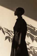 Canvas Print - a woman is wearing a black dress and standing in front of a white wall. the dress is long and black,
