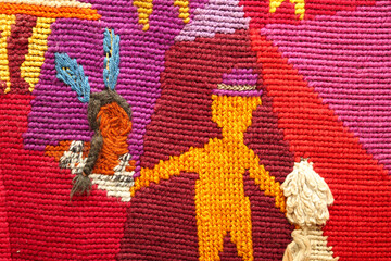 Large tapestry with indigenous person and settler holding hands. Close up of stitched mural or heirloom folk art tapestry. Wall carpet with happy colors with multiple stiches types. Selective focus.