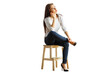 © peshkova - Woman seated on a wooden stool, dressed casually in a white top and jeans, looking thoughtful. Isolated on a clean white background, concept of contemplation