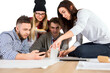 © peshkova - Group of four young adults collaborating at a desk, discussing work while using tools and smartphones, on an isolated white background