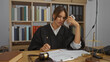 © Krakenimages.com - Young brunette hispanic woman in judicial robe working at an office and talking on phone while reviewing documents in a courtroom setting