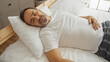 © Krakenimages.com - Middle-aged hispanic man sleeping peacefully in a cozy bed in a well-lit bedroom, showcasing comfort and restful sleep in a home environment.