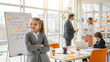 © NewFresh  - Portrait of a smiling little girl standing with her arms crossed in front of a whiteboard in the office