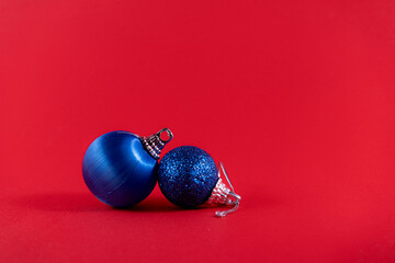 Wall Mural - Two blue Christmas ornaments on a vibrant red background, creating a festive contrast.