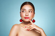 © Oleg Gekman - Portrait of beautiful young woman on blue background, red lipstick and festive makeup, Christmas toy earrings, shiny glowing skin, Winter holidays concept
