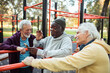 © Marko Geber - Senior men socializing and relaxing at outdoor park fitness area