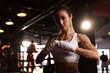 © kamonrat - Confident Female Boxer Wrapping Hands in Gym, Preparing for Training Session, Strong and Determined, Focused Athlete in Boxing Environment, Dedication and Fitness Lifestyle, Boxing Workout Prep