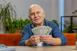 © Andrii Iemelianenko - Planning family budget. Happy senior man counting money cash calculate domestic bills at home. Mature old grandfather satisfied of income salary pension and saves money for planned vacation gifts