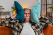 © Andrii Iemelianenko - Repair work at neighbors. Irritated Caucasian man cover ears with pillows annoyed by noisy loud music neighbors suffer from headache wishes silence. Thin walls at home flat without sound insulation