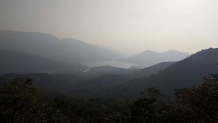 Wall Mural - Landscape view of misty hills and valleys with distant mountains fading into a hazy sky