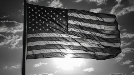 Wall Mural - Black and white image of the American flag waving in the wind against a cloudy sky.