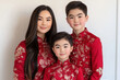 © AIPhoto - family celebrating Lunar New Year in traditional red outfits