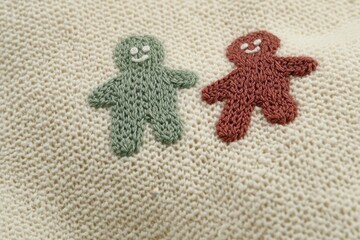 Two embroidered gingerbread figures on a textured fabric background.