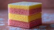 © QITIAN - Colorful sponges stacked artfully on a smooth surface.