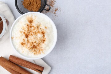 Wall Mural - Delicious rice pudding with cinnamon on light table, flat lay. Space for text