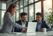 © natakot - In a bright, modern office filled with natural light, a woman enthusiastically points at a laptop screen while two men share a joyful moment, engaged in a collaborative discussion. Their professional