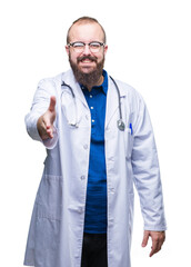 Wall Mural - Young caucasian doctor man wearing medical white coat over isolated background smiling friendly offering handshake as greeting and welcoming. Successful business.