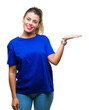 © Krakenimages.com - Young beautiful woman wearing casual blue t-shirt over isolated background smiling cheerful presenting and pointing with palm of hand looking at the camera.