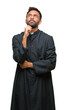 © Krakenimages.com - Adult hispanic catholic priest man over isolated background with hand on chin thinking about question, pensive expression. Smiling with thoughtful face. Doubt concept.