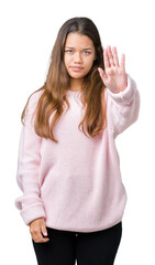 Wall Mural - Young beautiful brunette woman wearing pink winter sweater over isolated background doing stop sing with palm of the hand. Warning expression with negative and serious gesture on the face.