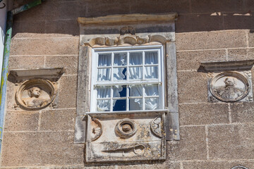 Wall Mural - A historic building facade with a window adorned with intricate stone carvings and framed by ornate details