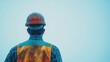 © Giovanni - Construction worker in safety vest and hardhat looking towards empty sky on a minimalistic background from the back perspective