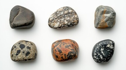 Leinwandbilder - Collection of smooth beach stones showcasing diverse textures and colors arranged on a white background for natural design inspiration