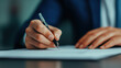© saichon - A close-up of a person's hand writing on a piece of paper with a pen, showcasing a professional and focused atmosphere.