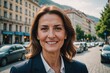 © ThomasLENNE - Close portrait of a smiling senior Montenegrin businesswoman looking at the camera, Montenegrin big city outdoors blurred background