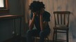 © Jack - Person sitting alone in dimly lit room, holding head with both hands, looking distressed. Sparse furnishings highlight isolation and emotional pain.