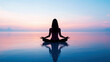 © Axel Bueckert - woman practicing yoga in lotus pose for meditation and mindfulness at dawn on calm ocean water