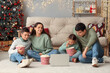 © Pixel-Shot - Happy family with popcorn watching Christmas movie on laptop at home