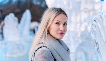 Wall Mural - Woman with frost tipped hair poses in front of stunning ice sculpture display during winter festival