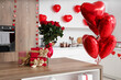 © Pixel-Shot - Gift boxes and bouquet of roses on wooden table in kitchen, closeup. Valentine's Day celebration